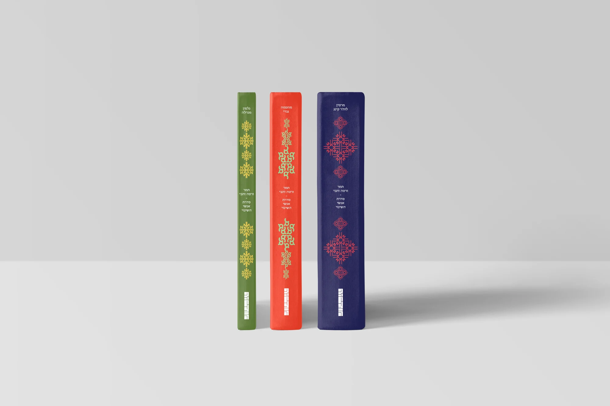 The three book spines side by side: green, red and navy, each with a patterned ornament and a Hebrew title